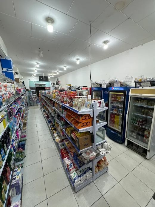 Corredor de mercearia do Mercadão do Mestre, com prateleiras abastecidas e geladeiras de bebidas
